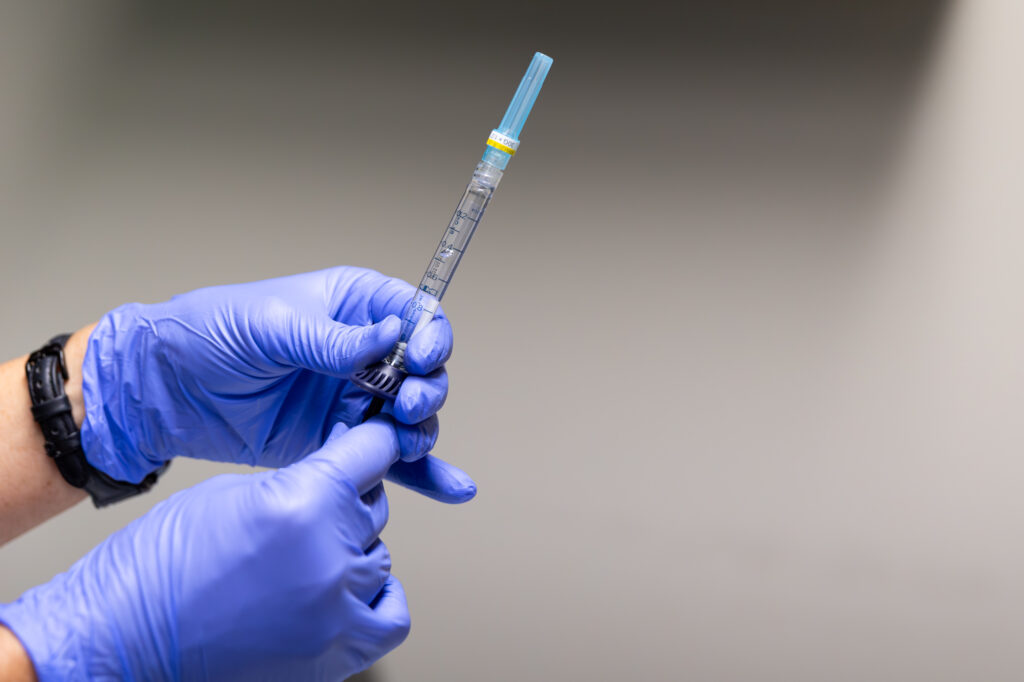 a nurse with blue gloves holds a syringe of lip filler in St. Petersburg