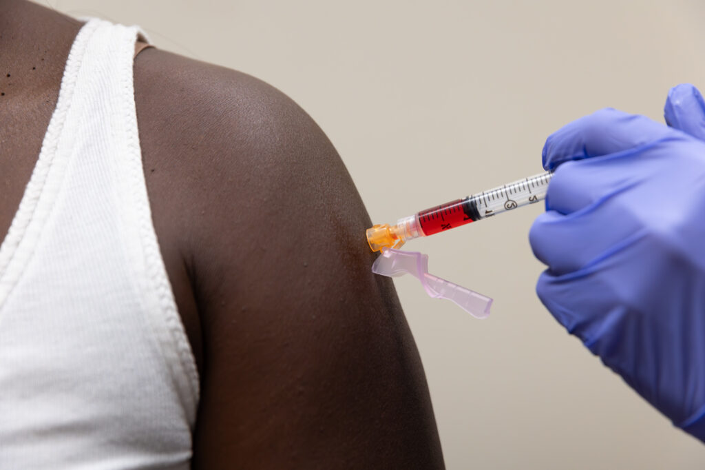 Close-up of a medical professional wearing blue gloves injecting semaglutide in Clearwater into a patient's arm