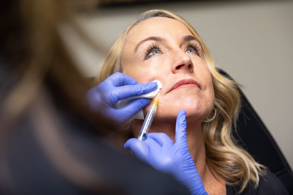 Close-up of a professional with blue gloves injecting a female patient with Sculptra in St. Petersburg