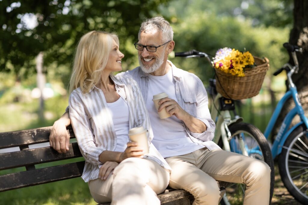 A mature couple laughs together on a park bench after a man receives TRT treatments in St. Petersburg