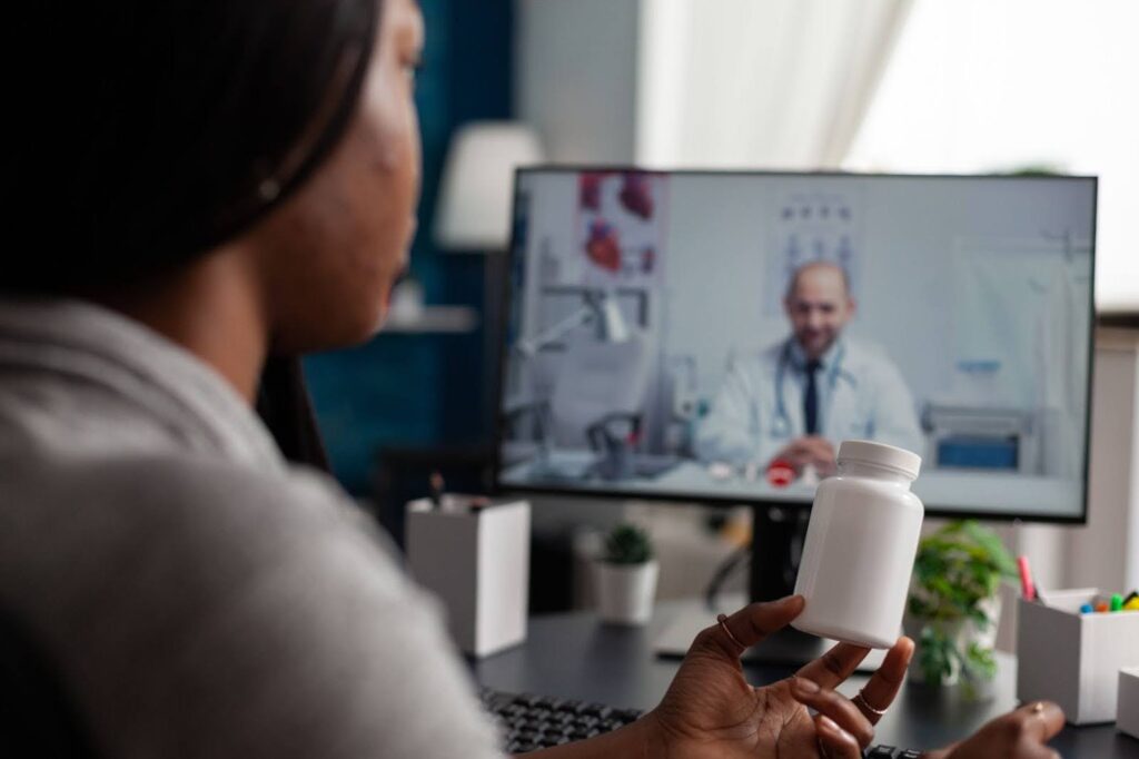 A patient meets with her doctor on her computer while holding a medication bottle after receiving a telemedicine weight loss prescription in Florida